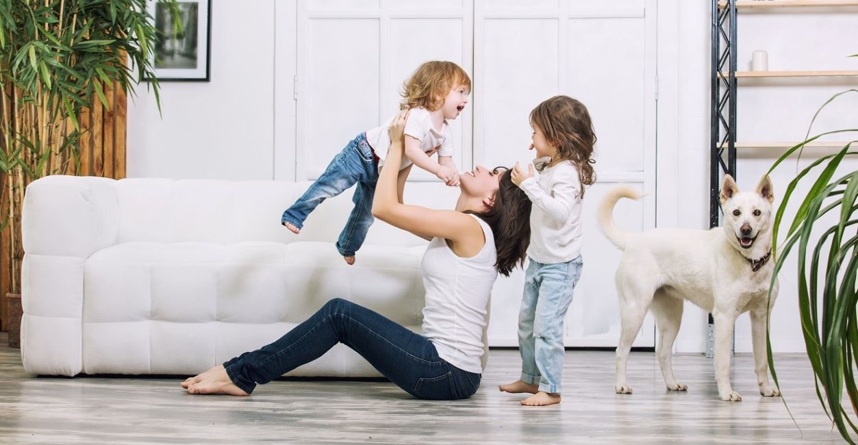 Mother Playing With Children And Dog In Clean Home